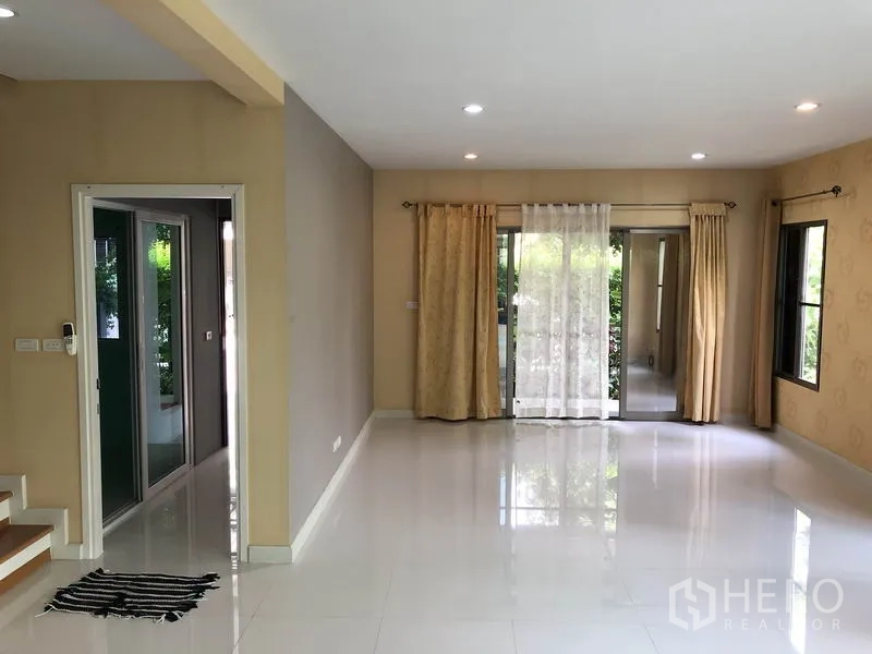 独立式住宅 出租在Suan Luang, Bangkok - 采光充足的客厅，亮面地砖、筒灯与通往花园的推拉门