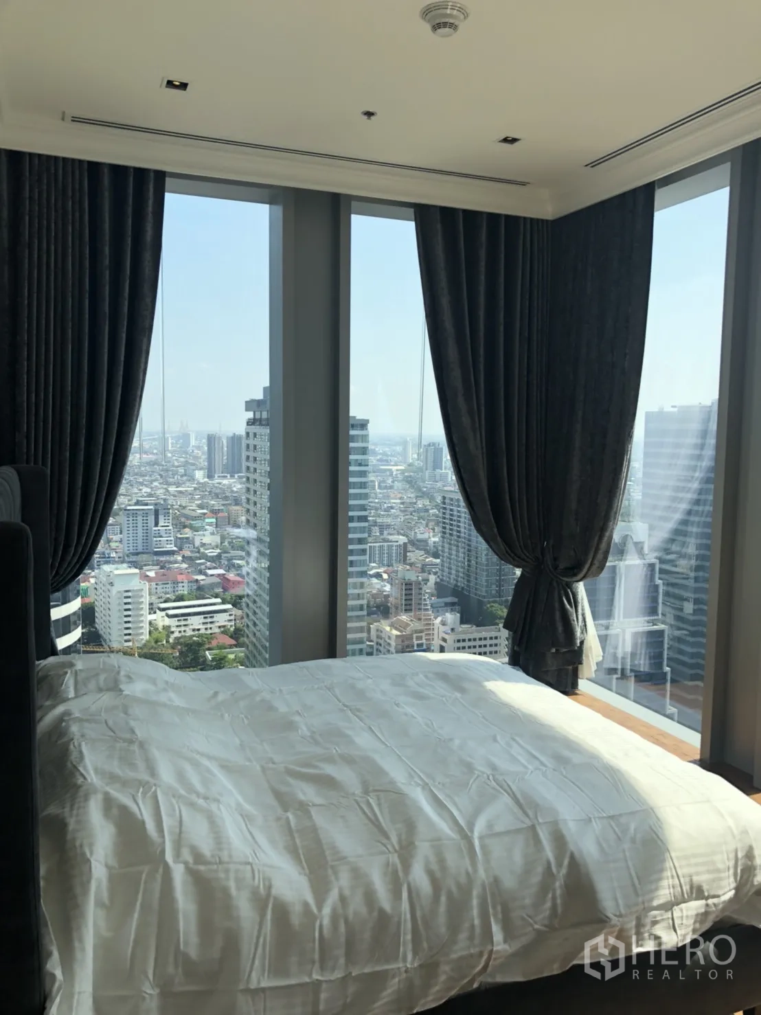 คอนโด ให้เช่าในBang Rak, Bangkok - ห้องนอนมุมกระจกเต็มผนังพร้อมม่านทึบ มองเห็นสกายไลน์กรุงเทพฯ
