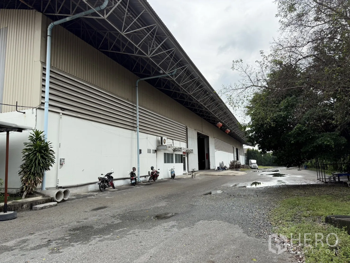 Factory for rent in Bang Phli, Samut Prakan - Side facade of the metal-clad warehouse with deep eaves and drainage pipes.