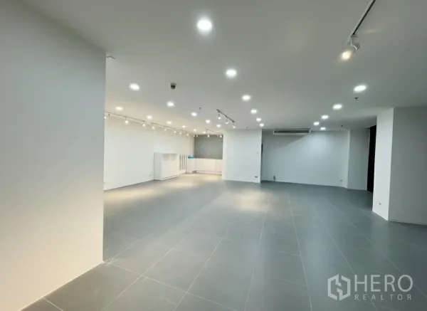 Retail Space for rent - Spacious open-plan interior with grey tile flooring, white walls, and recessed plus track lighting.