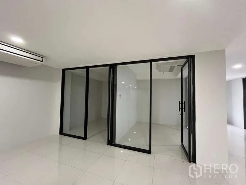 Office Space for rent in Prawet, Bangkok - Open workspace with sliding glass doors leading to a meeting room, glossy tiled floor and recessed lights.