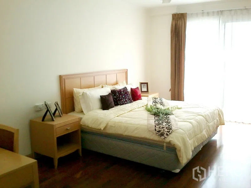 Condominium for rent in Khlong Toei, Bangkok - Bright double bedroom with floor-to-ceiling curtains and balcony access.