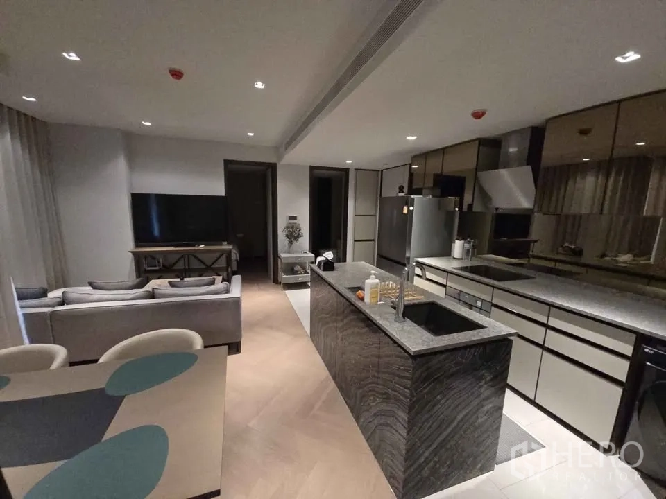 公寓 for rent in Watthana, Bangkok - 开放式客厅配L型沙发、餐桌与石材中岛厨房。