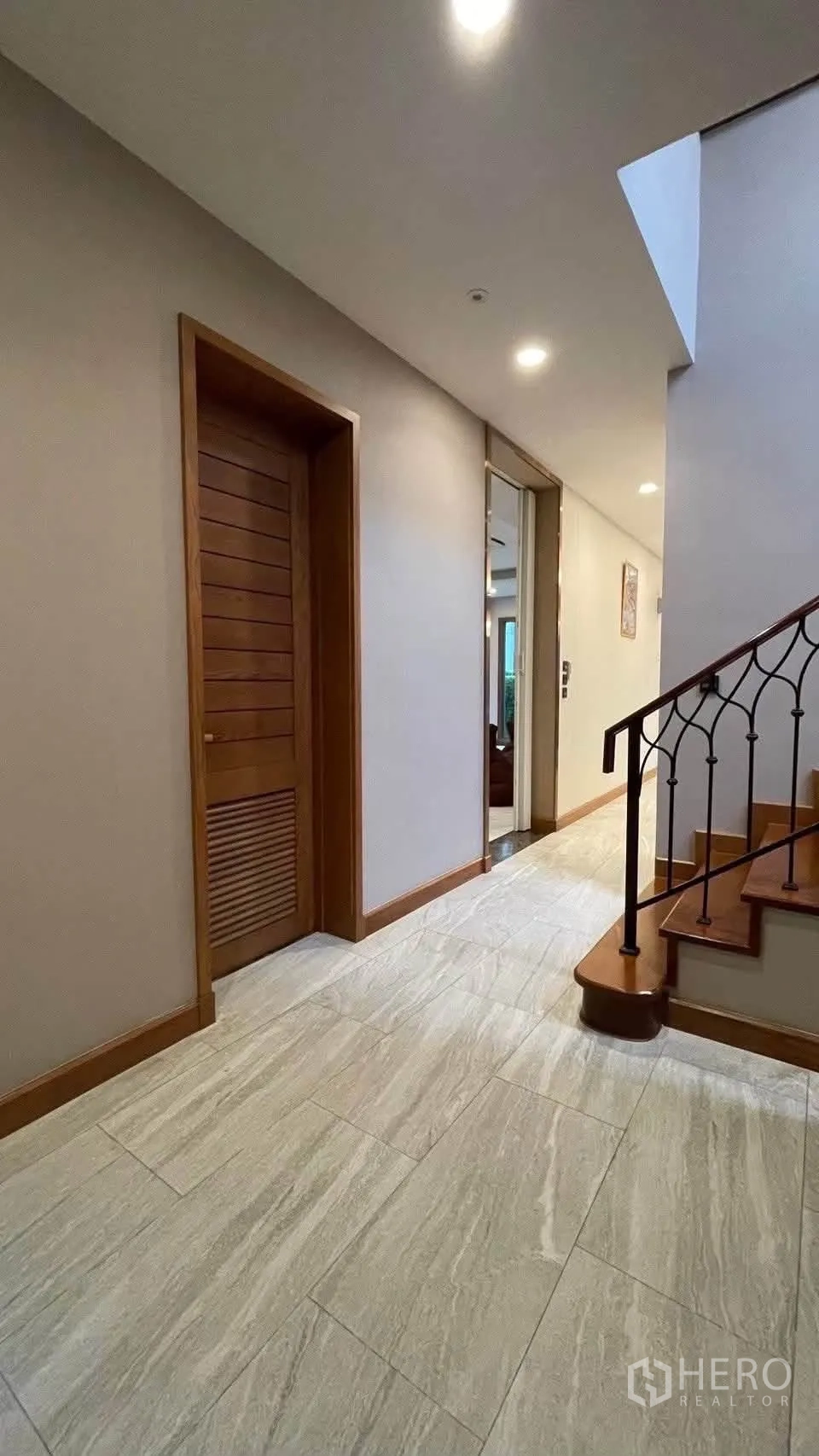 Detached House for rent in Prawet, Bangkok - Ground-floor corridor with stairs and light stone-look tile flooring.