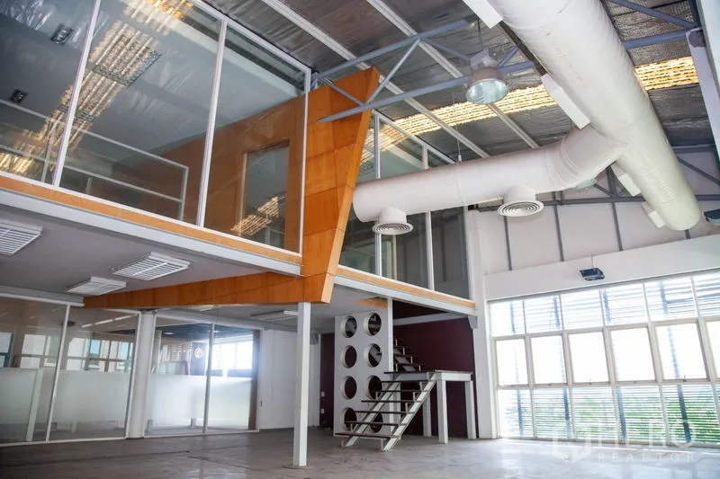 Warehouse for rent in Prawet, Bangkok - Glass-walled mezzanine office with metal staircase, large windows and white air ducts inside a Bangkok industrial warehouse.