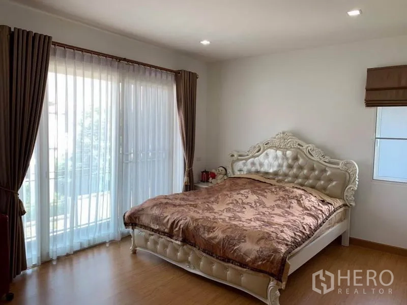 Detached House for sale in Suan Luang, Bangkok - Master bedroom with tufted bed, large windows and access to the balcony.