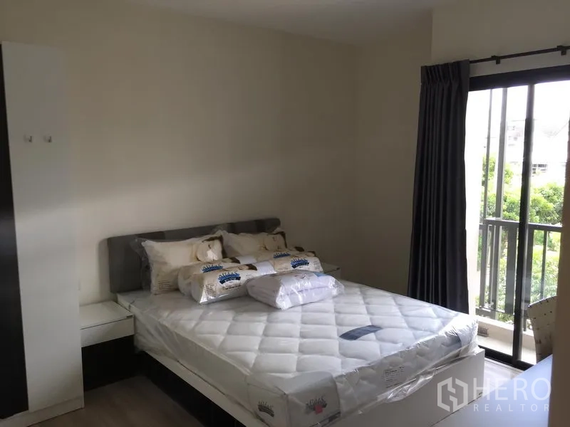 Townhouse for rent or sale in Saphan Sung, Bangkok - Cozy bedroom with double bed, wardrobe and a balcony overlooking greenery.