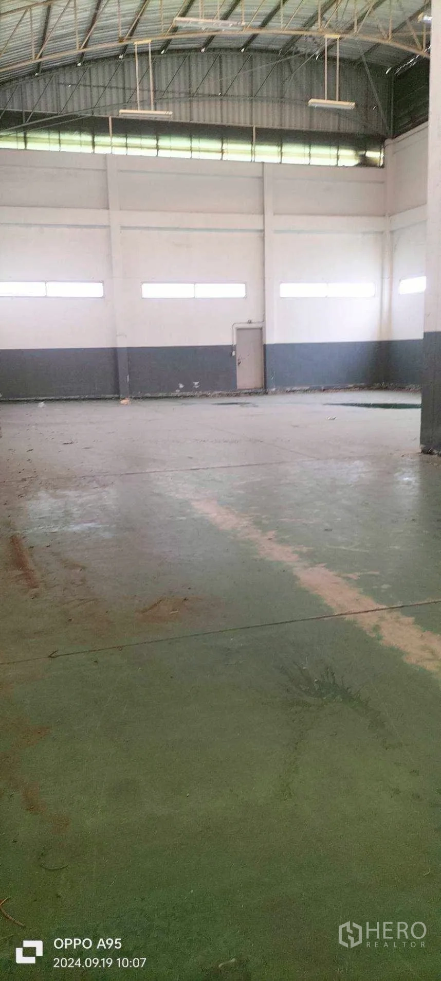 Factory for rent in Khlong Luang, Pathum Thani - Empty factory floor with side windows and a metal service door.