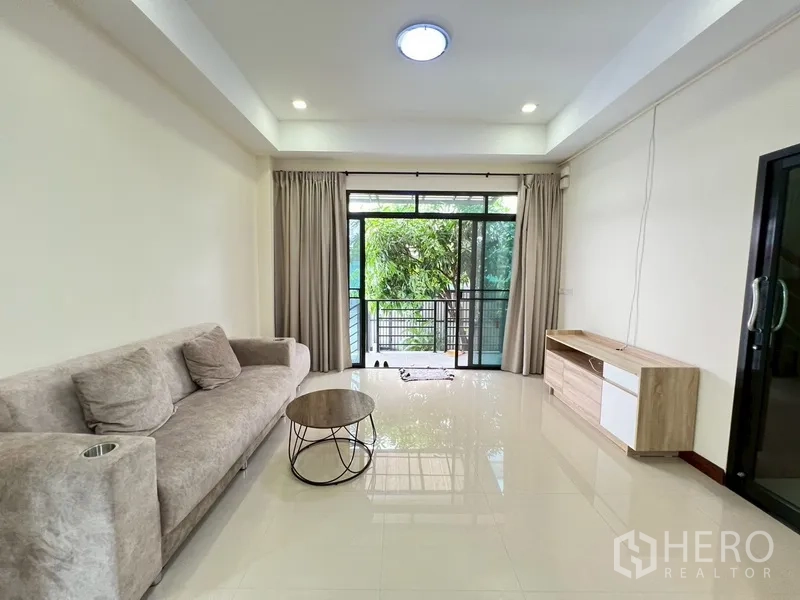บ้าน ขายในPhra Khanong, Bangkok - ห้องนั่งเล่นมีประตูกระจกบานเลื่อนออกสู่ระเบียงและวิวสวน