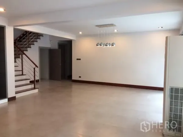 Detached House for rent or sale in Khan Na Yao, Bangkok - Open-plan lounge and dining area with pendant lights and a staircase