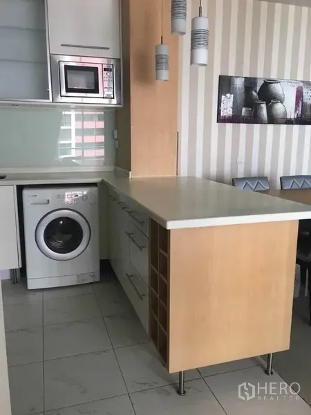 公寓 出租在Bang Rak, Bangkok - 紧凑厨房配吧台、洗衣机、微波炉与吊灯。