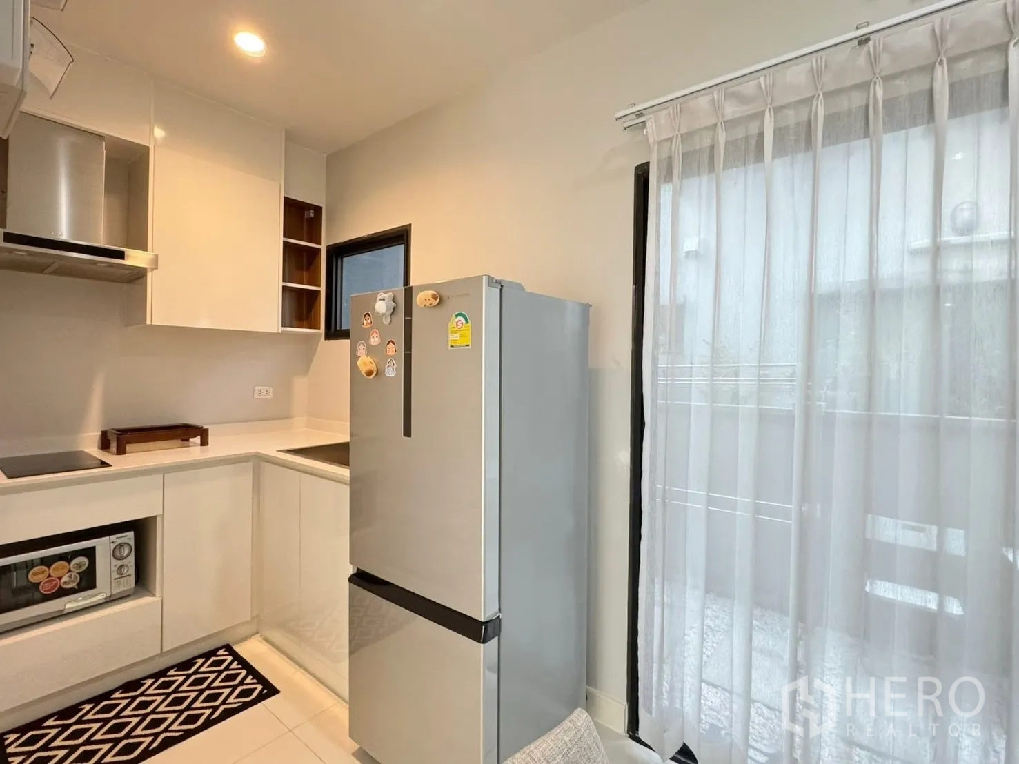 Townhouse for rent in Saphan Sung, Bangkok - Bright L-shaped kitchen with white cabinets and stainless refrigerator.