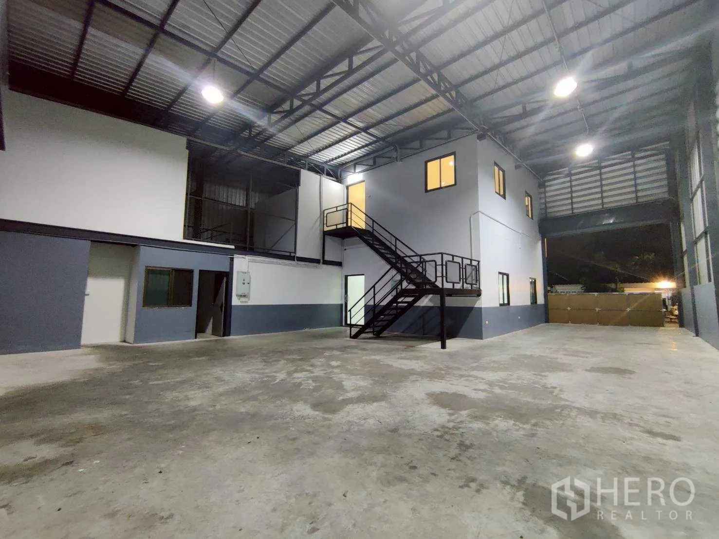 Warehouse for rent in Lam Luk Ka, Pathum Thani - Spacious storage hall with metal wall vents and an internal office block.
