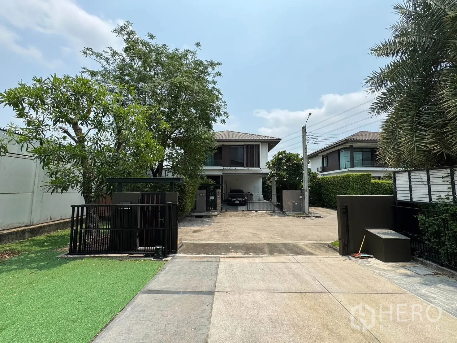 Detached House for rent in Prawet, Bangkok - Gated front driveway with a wide parking area and mature trees.