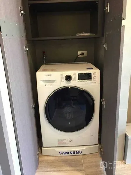 Condominium for rent in Bang Rak, Bangkok - Front-load washing machine neatly concealed in a cabinet within the condo.