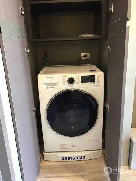 Condominium for rent in Bang Rak, Bangkok - Front-load washing machine neatly concealed in a cabinet within the condo.