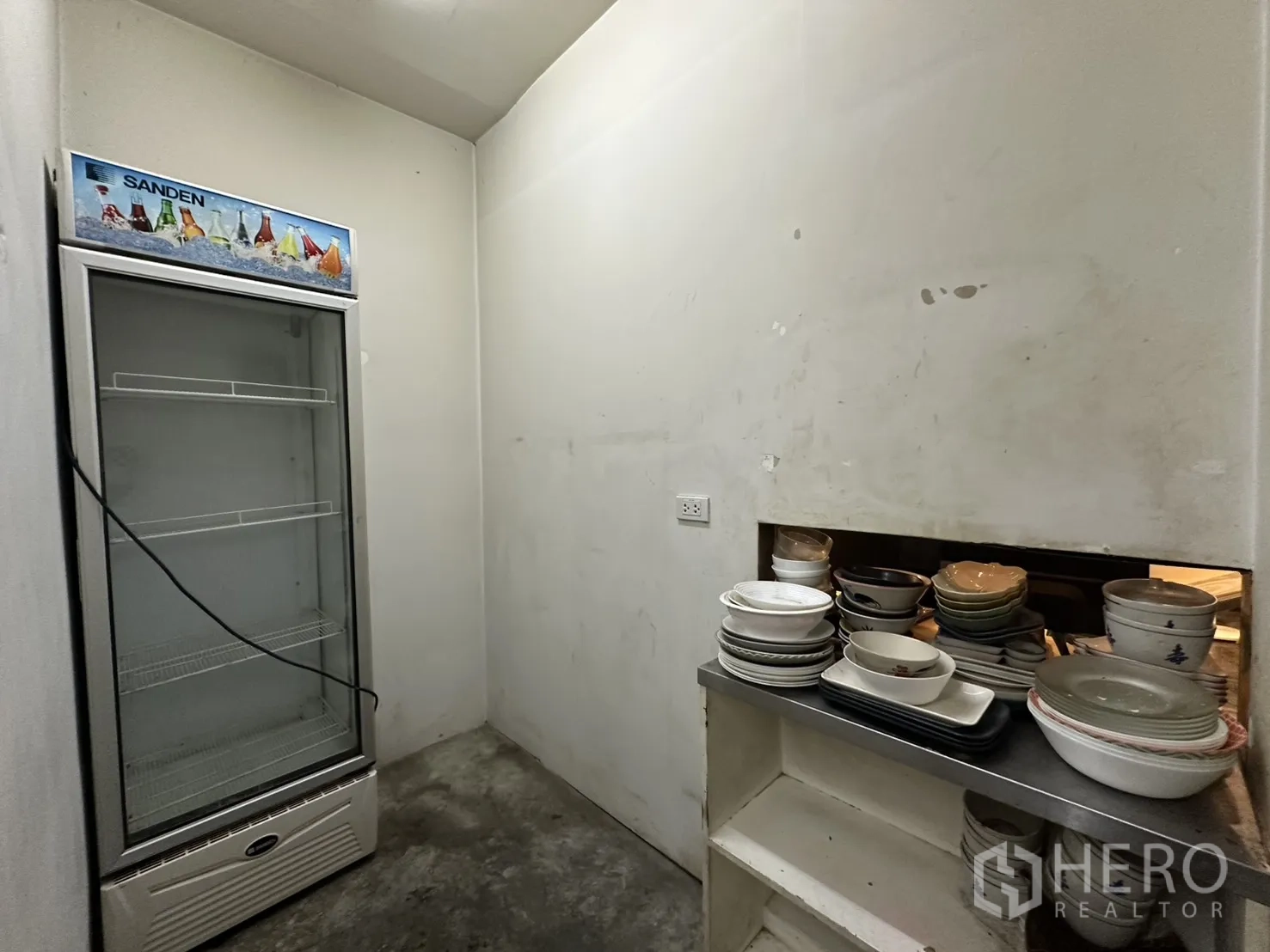 Retail Space for rent in Watthana, Bangkok - Pantry space with tall display refrigerator and stacked tableware.