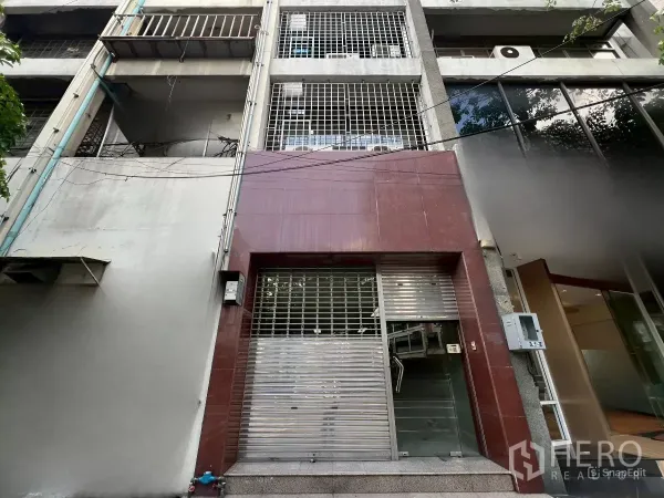 Shophouse for rent in Bang Rak, Bangkok - Street-level view of a five-storey Silom shophouse façade with metal security shutter and grille.