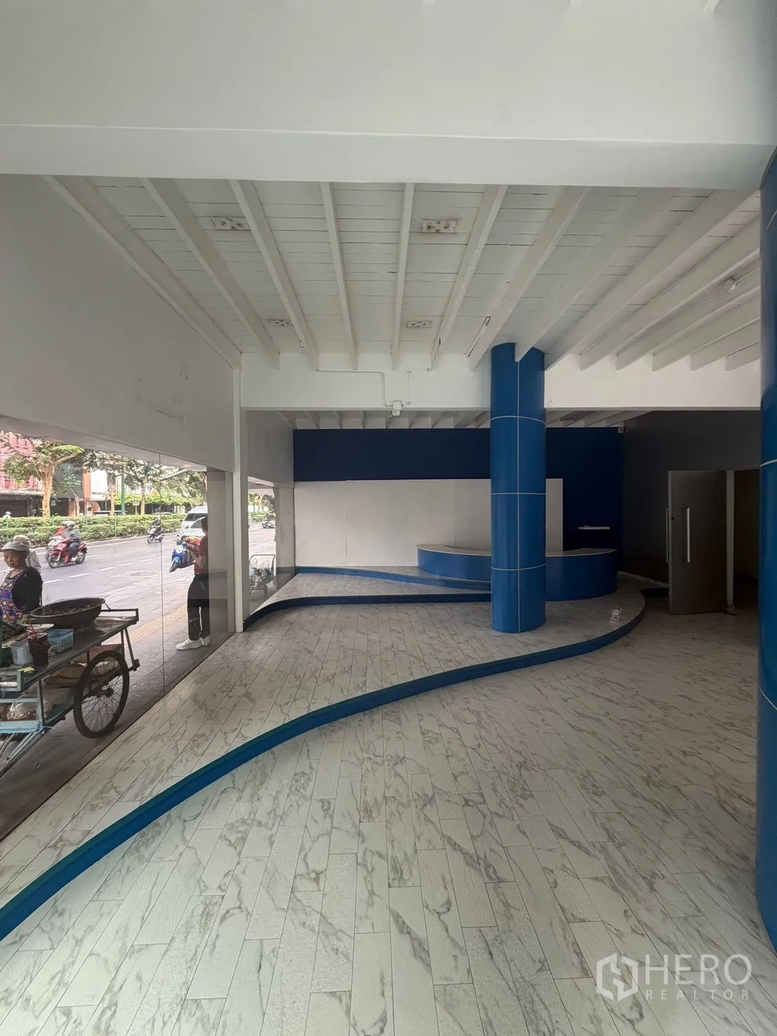 店屋 for rent in Watthana, Bangkok - 一层展示厅，仿石纹地砖、弧形平台与整面玻璃橱窗。