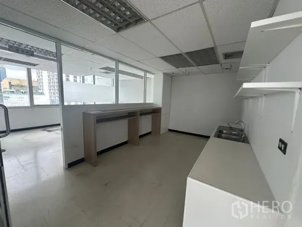 Office Space for rent - Office pantry area with sink, open shelving and a high counter beside internal glass windows.