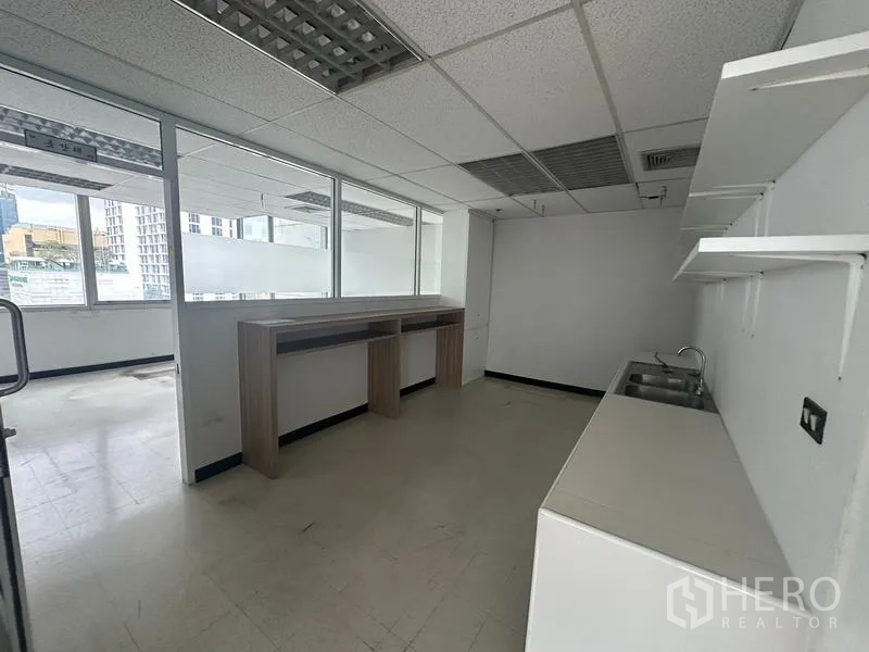 Office Space for rent - Office pantry area with sink, open shelving and a high counter beside internal glass windows.