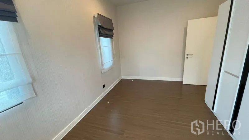 Detached House for rent in Bang Kapi, Bangkok - Secondary bedroom with wood floor, two windows and a white wardrobe.