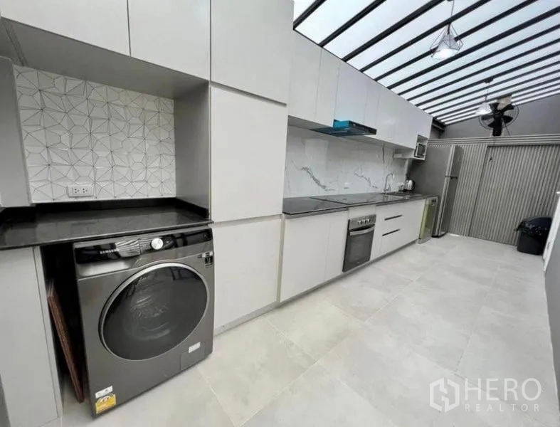 联排别墅 出租在Wang Thonglang, Bangkok - 厨房另一角度，含灶台、洗衣机与充足柜体。