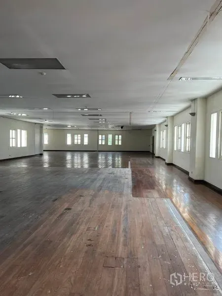 办公空间 出租在Khlong Toei, Bangkok - 长形办公大厅，混色木地板、多扇窗户与吊顶灯带贯穿空间。