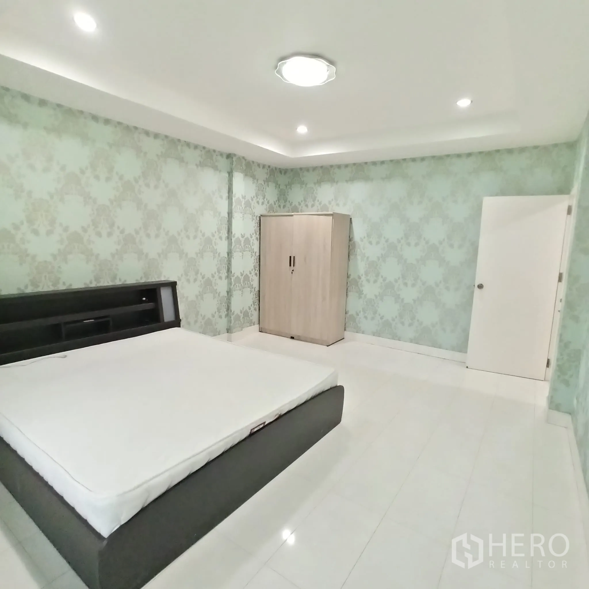 Townhouse for rent in Wang Thonglang, Bangkok - Spacious bedroom with patterned wallpaper and a bed frame.