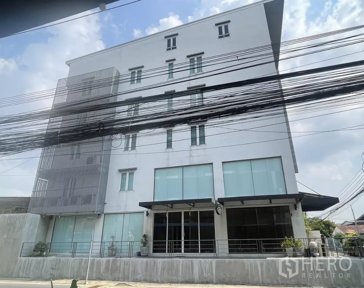 带办公室的家 出租在Suan Luang, Bangkok - 白色办公楼正立面，配大面积磨砂玻璃与阳台细节。