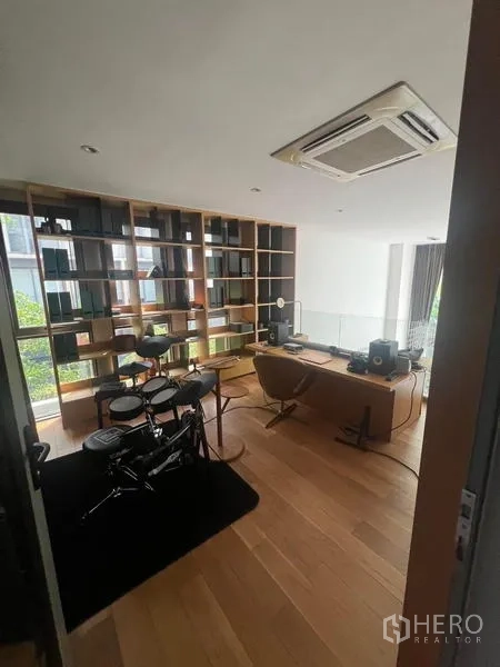 Townhouse for rent - Home office with built-in bookshelf, wooden floors and an electronic drum kit overlooking greenery