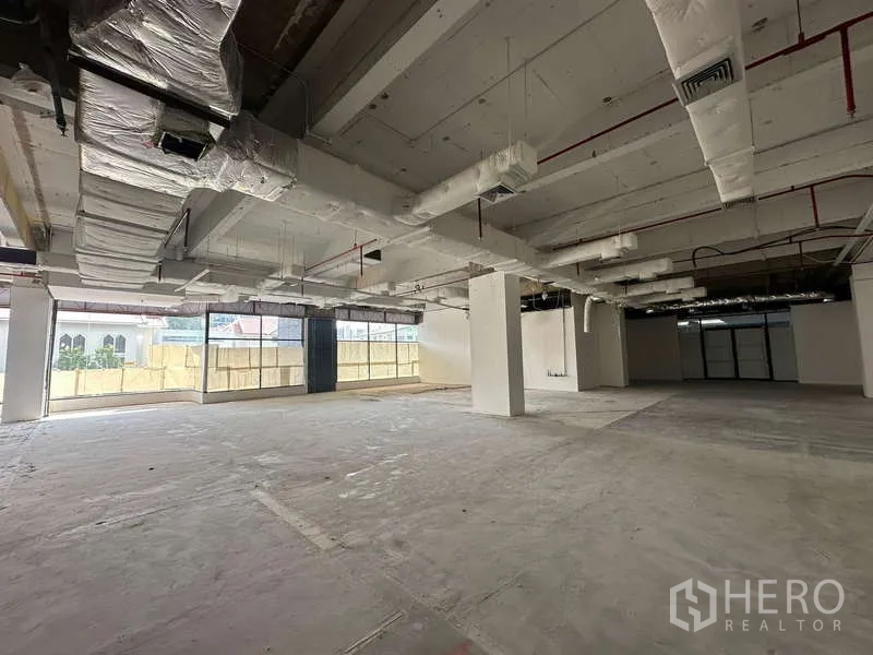 Office Space for rent - Open-plan shell office with high ceiling, exposed ductwork and floor-to-ceiling windows.