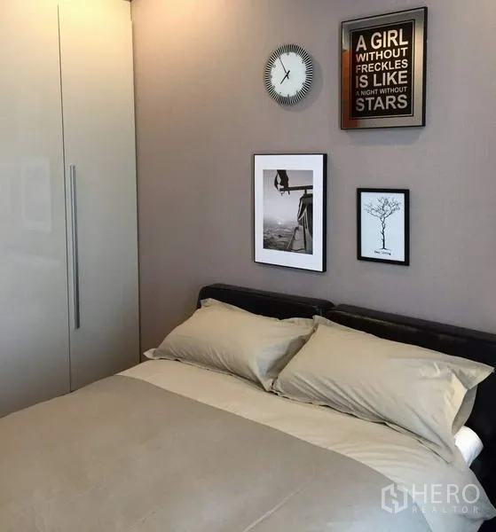 Condominium for rent in Khlong Toei, Bangkok - Secondary bedroom with double bed, built-in wardrobe and framed wall art on a neutral wall.