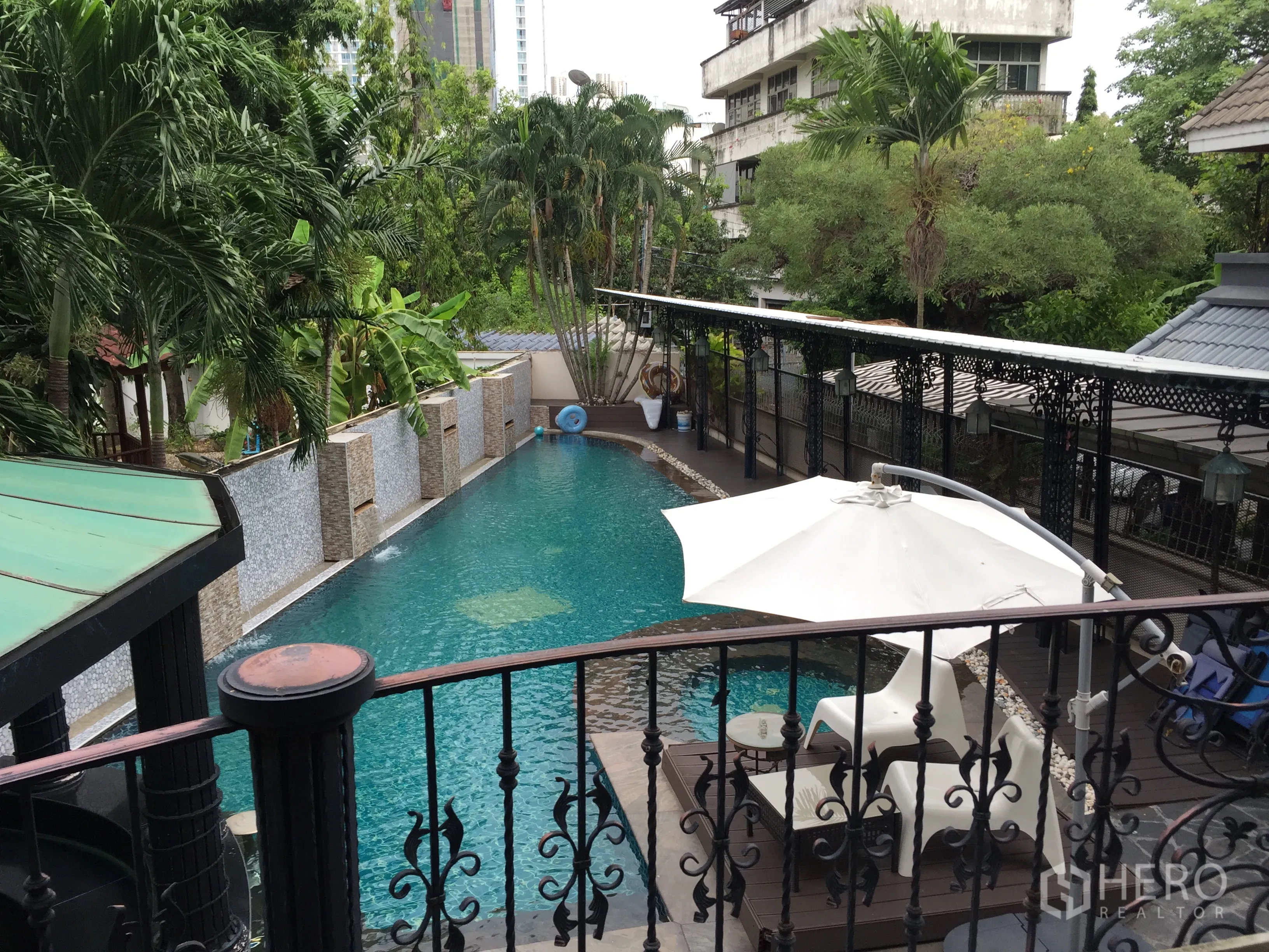 Condominium for rent in Khlong Toei, Bangkok - Outdoor swimming pool with palm trees, sun loungers and a shaded deck.