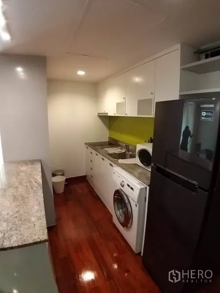 Condominium for rent or sale in Pathum Wan, Bangkok - Kitchen corridor with appliances, granite counters and a green backsplash.