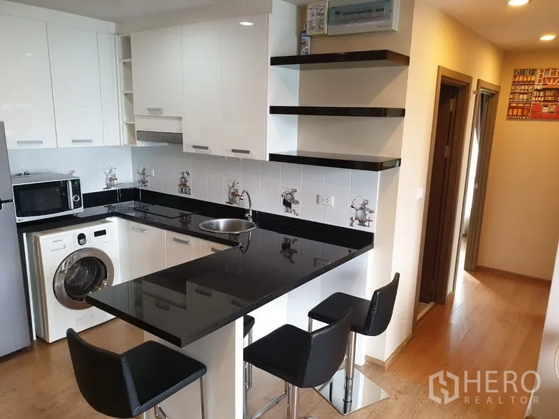 公寓 出租在Watthana, Bangkok - 白色橱柜厨房，黑色花岗岩台面与吧椅，内置洗衣机