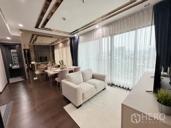 Condominium for rent in Watthana, Bangkok - Bright lounge with floor-to-ceiling windows, sheer curtains, and wood floors.