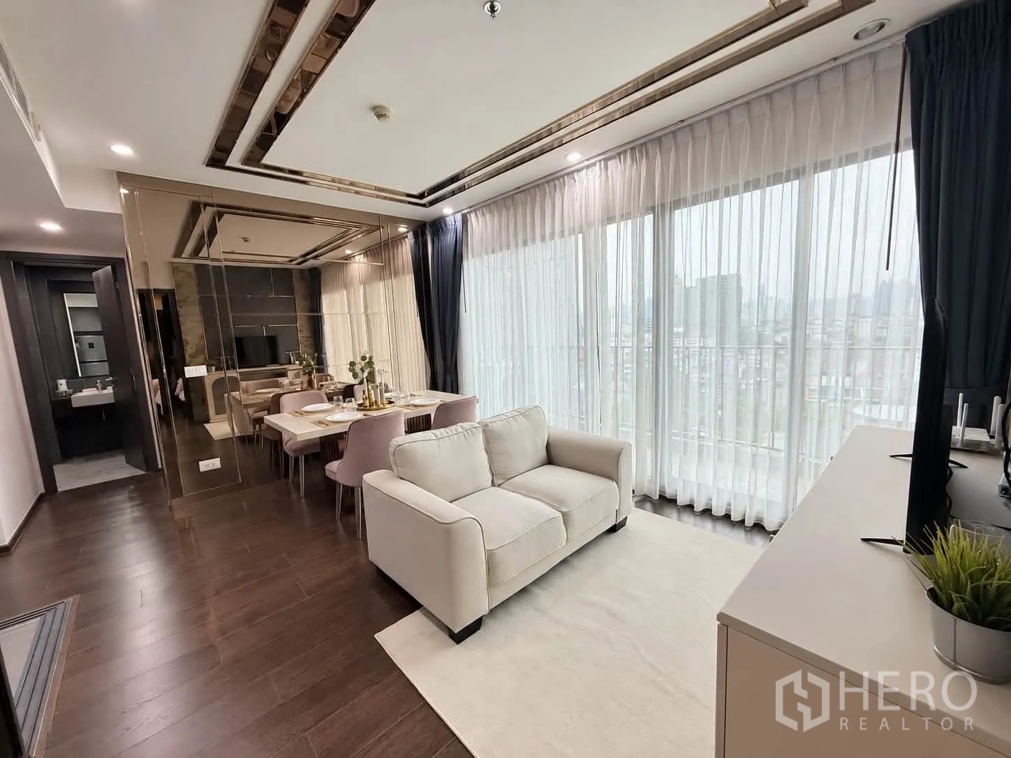 Condominium for rent in Watthana, Bangkok - Bright lounge with floor-to-ceiling windows, sheer curtains, and wood floors.