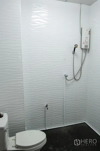 Home Office for rent in Khlong Toei, Bangkok - Bathroom with textured white tiles and electric shower heater.
