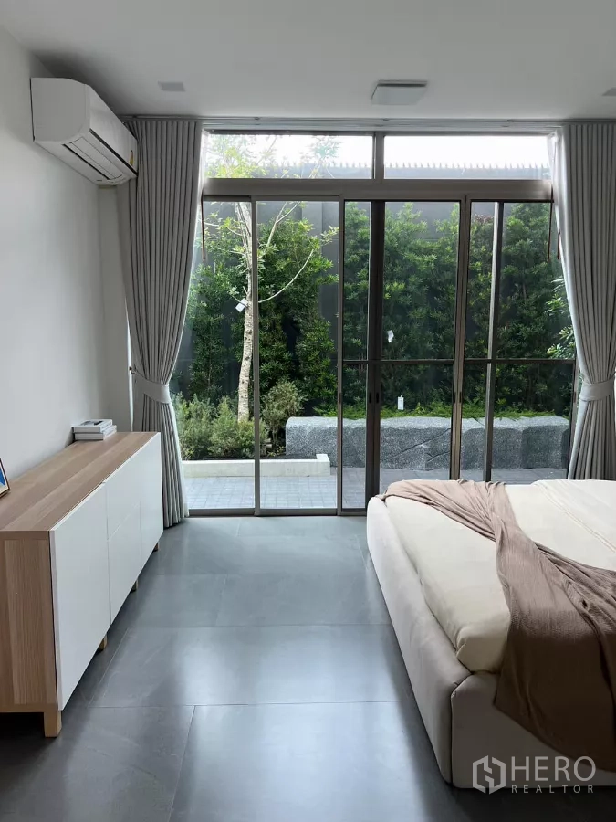 Detached House for rent in Saphan Sung, Bangkok - Ground-floor bedroom with sliding glass doors opening to a private garden.