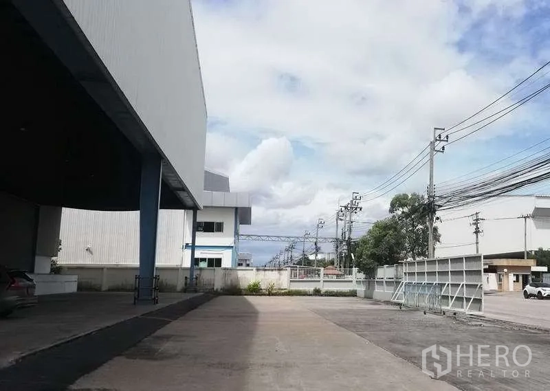 คลังสินค้า ให้เช่าในBang Phli, Samut Prakan - ทางวิ่งและลานนอกอาคารข้างโกดัง มีกำแพงรั้ว สายไฟ และทางเข้า-ออก