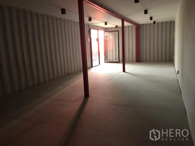 办公空间 出租在Khlong Toei, Bangkok - 长条形工业风办公室内部，红色立柱、轨道灯与玻璃滑门入口。