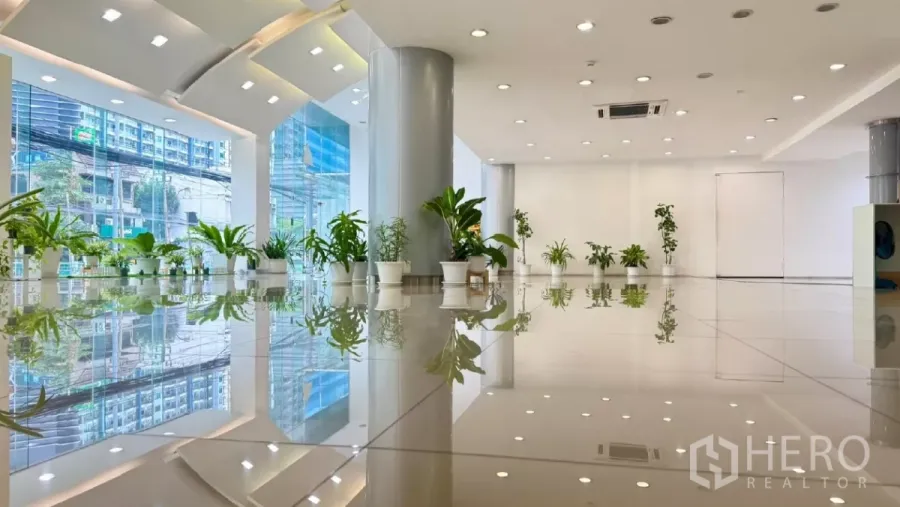 Retail Space for rent in Huai Khwang, Bangkok - Bright retail showroom with floor-to-ceiling glass, high ceiling and glossy tiles overlooking a busy city street.