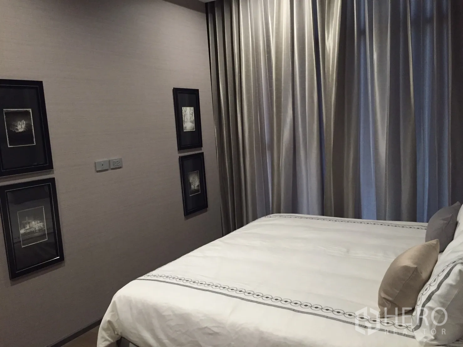 公寓 出租在Bang Rak, Bangkok - 温馨卧室，白色床品、墙面装饰画与到顶遮光窗帘。