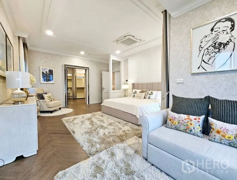 Detached House for rent or sale in Saphan Sung, Bangkok - Spacious master bedroom with seating area, walk‑in closet access and wood floors.