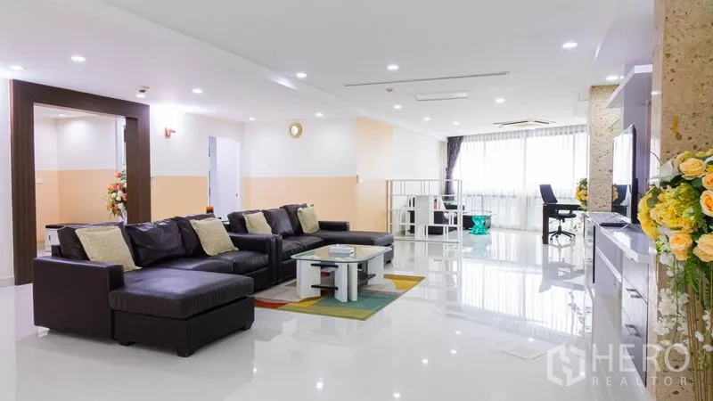 Condominium for rent or sale in Khlong Toei, Bangkok - Wide lounge with sectional sofa, desk area and floor-to-ceiling style windows.