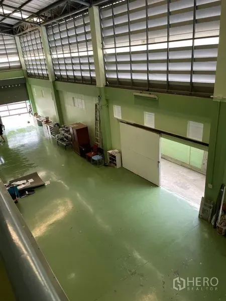 Warehouse for rent in Khan Na Yao, Bangkok - High-bay storage hall with ventilation louvers, epoxy floor, and a wide roller door for access.