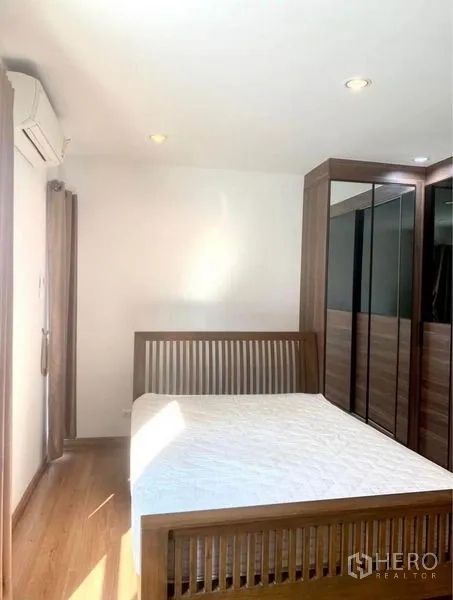 Townhouse for rent in Suan Luang, Bangkok - Second bedroom with wooden bed frame, built-in wardrobes and air conditioning.