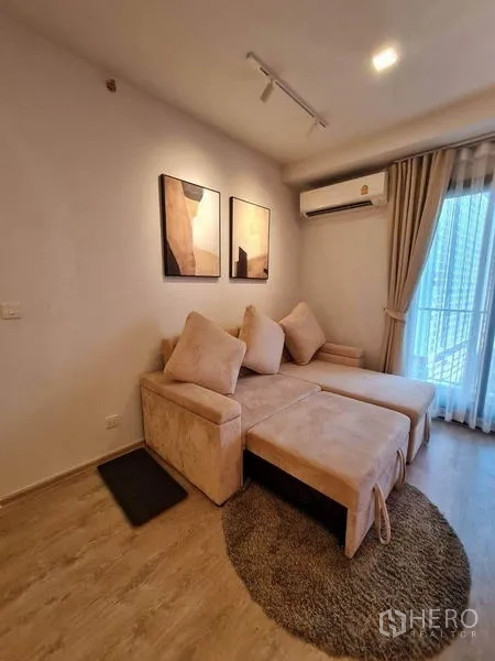 Condominium for rent - Cozy living area with an L-shaped sofa, rug, abstract wall art, air conditioning and balcony door.