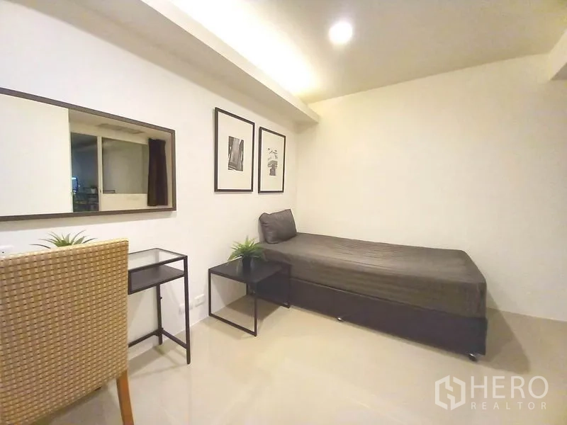 Condominium for rent in Khlong Toei, Bangkok - Second bedroom with single bed, desk, wall art and side tables.